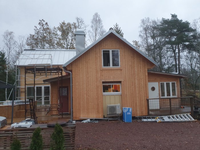 Ett hus med dubbelfalsad zinkad plåt på taket och träfasad, byggställningar syns vid ena gaveln.