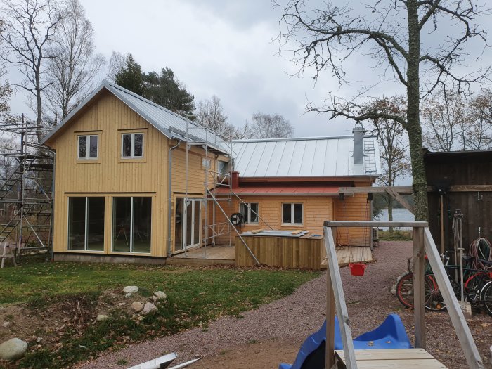 En tvåvåningshus under renovering med ny dubbelfalsad zinkad plåt på taket och ställningar runtom.