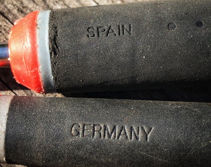 Närbild av två handtag på verktyg, det övre märkt "SPAIN" och det nedre "GERMANY".