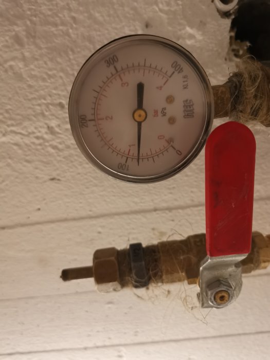 Manometer visar trycket i en radiatorkrets under provtryckning, med fokus på mätaren och en röd ventil.