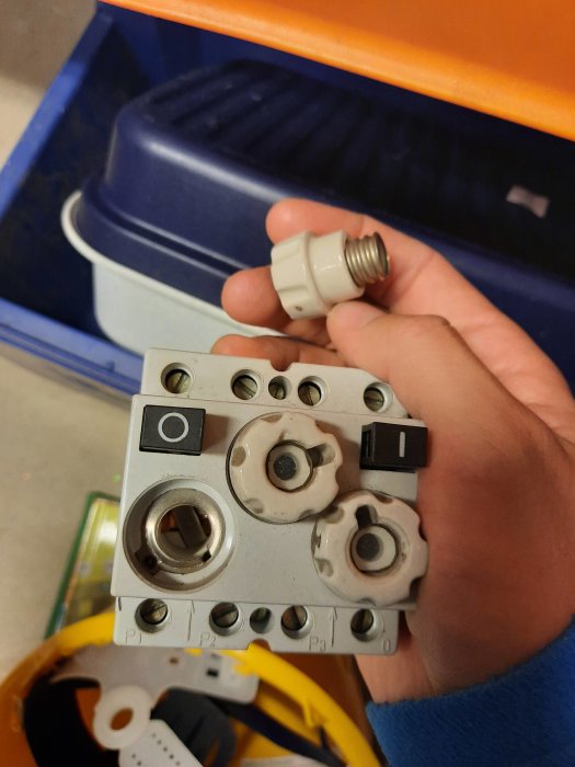 Hand håller ett gammalt elrelä funnet på loppis, med tydliga användningsspår och äldre knappar.