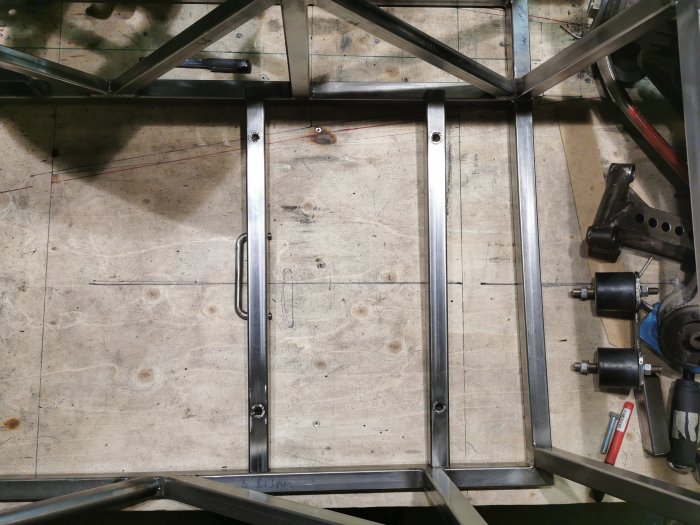 Stolsfäste i konstruktion med 25x25x2 rör och verktyg på en verkstadsbänk.