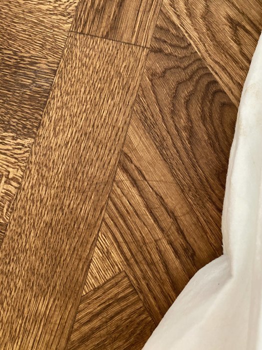 Närbild av ny fiskbensparkett i ek med märken och en strukturerad yta.