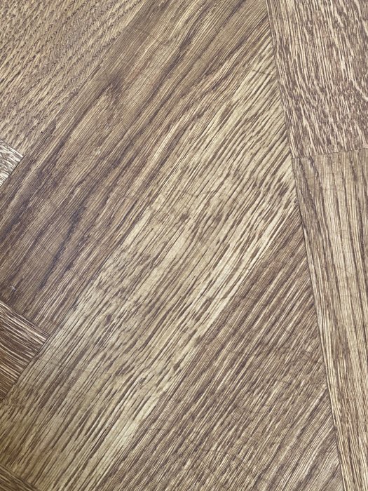 Ny lagd fiskbensparkett i ek med synliga märken och borstad yta under behandling.