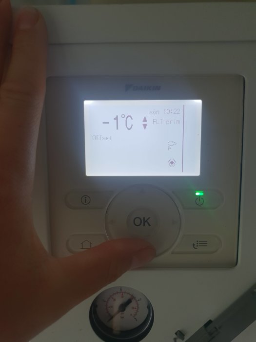 Hand som pekar på en Daikin-termostat som visar -1°C, med texten "Offset" och indikatorn "FLT prim", bredvid tryckmätare som visar 0.