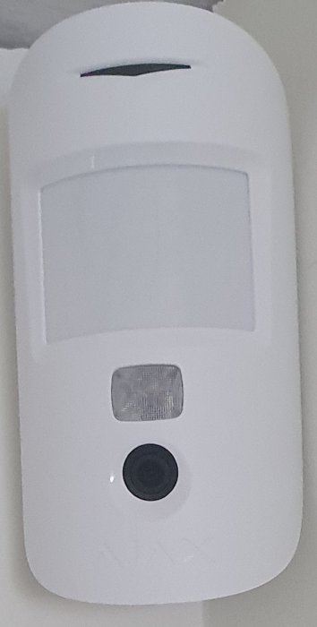 Vit motioncam installerad på vägg, med sensor och kamera synlig.