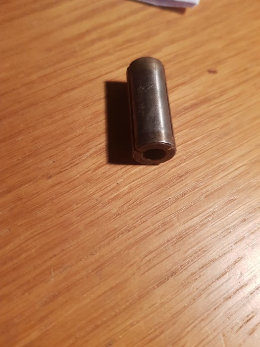 Metallhylsa liggande på träyta.