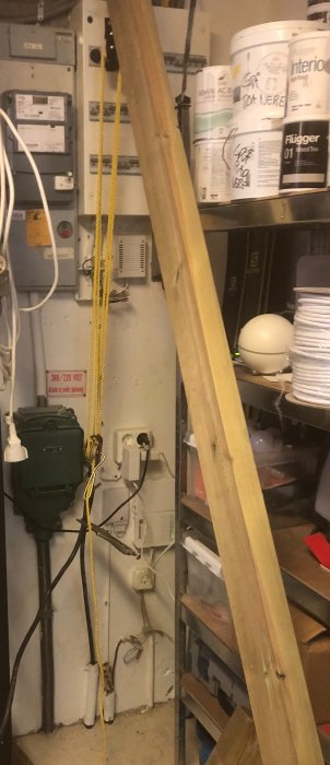 En verktygsvägg med elcentral, en träregel med talja och rep samt olika byggmaterial och färgburkar.