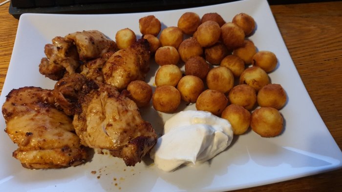 Tallrik med air fryer tillagad kycklingfilé, gyllene potatiskrokanter och en klick aioli.