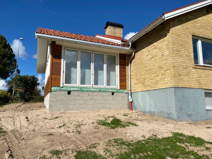 Utbyggnad på ett hus från 1959 med kombination av gul tegel och cederfasad under konstruktion.