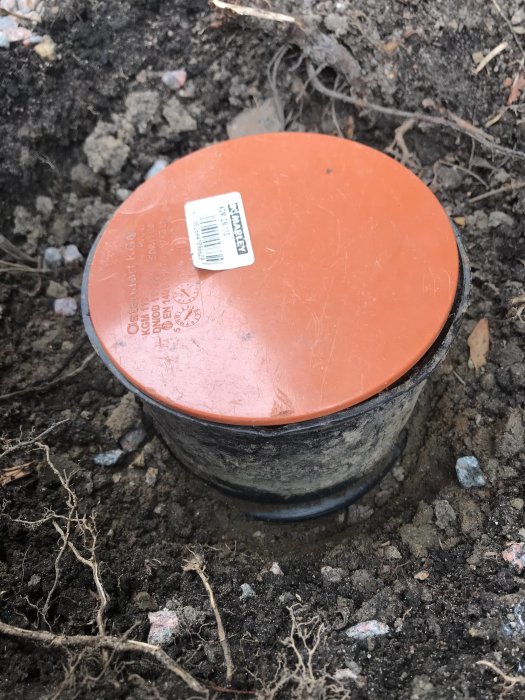 Markrörspropp installerad i ett dräneringsrör i jord, med synlig etikett.