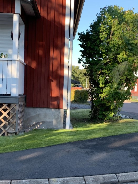 Huset hörn med synliga fuktfläckar upp till 40cm på den putsade sockeln, i skuggan, med singelspalt och stenplattor.