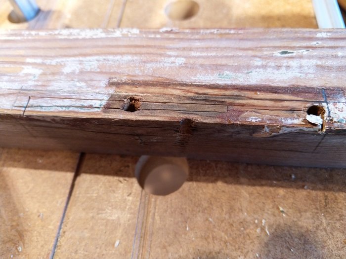 Gammal fönsterbåge med spräckt trä och borttagen färg under renovering.