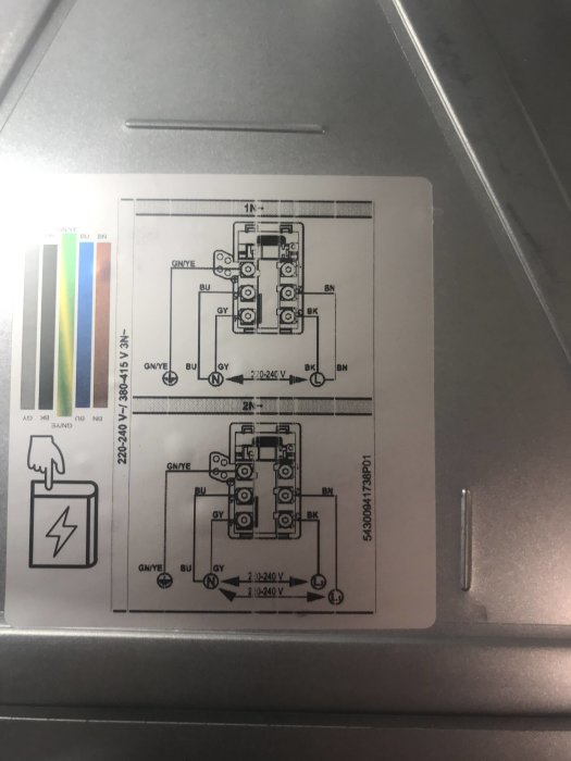 Elektrisk kopplingsschema för induktionshäll med enkel- och trefasanslutning, klistrad på hällens metallunderdel.