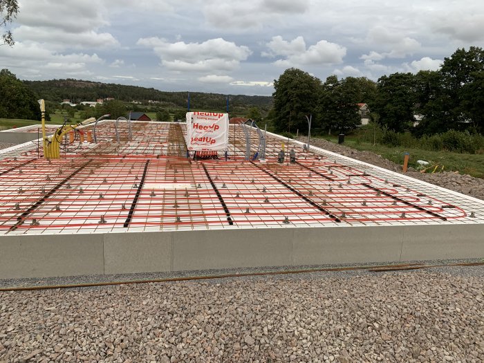 Konstruktion av kantbalk med distanser och armeringsnät på en grund med isoleringsmattor i ett byggprojekt.