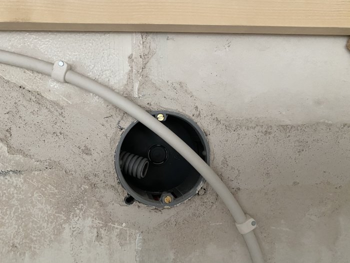 Öppen kopplingsdosa med kablar i taket, felaktig installation synlig.