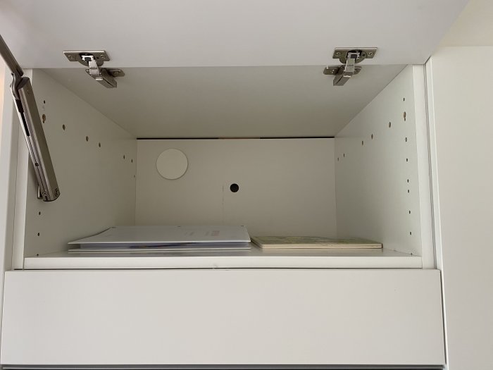 Inuti ett överskåp med synliga kopplingsdosor och klamrad kabel, tecken på amatörmässig elinstallation.