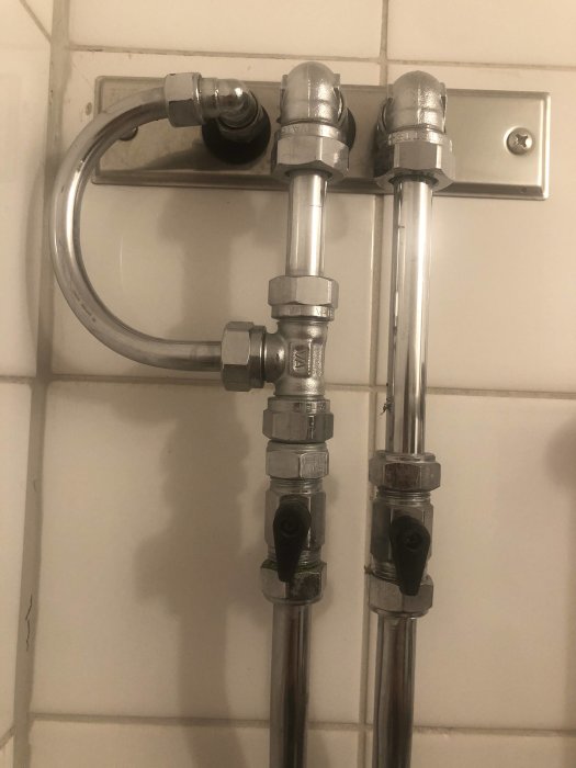 Gamla vattenledningar och avstängningsventiler på en badrumsvägg, del av Mora Link-systemet.