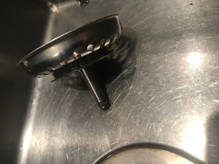 En uppochnervänd korgsil i metall i ett slitet diskho av rostfritt stål.