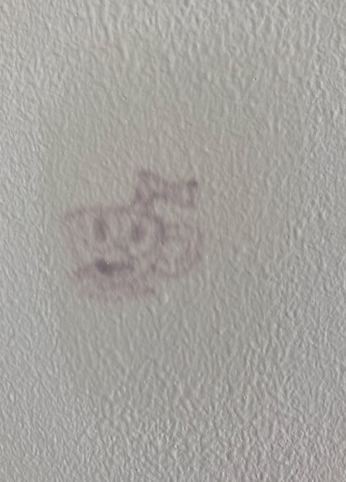 Vägg med fläckar efter barns målning som lyser igenom trots övermålning.