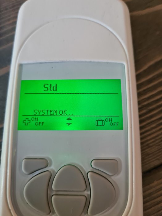 Handhållen enhet med display som visar meddelandet "SYSTEM OK" och flera av/på-symboler.