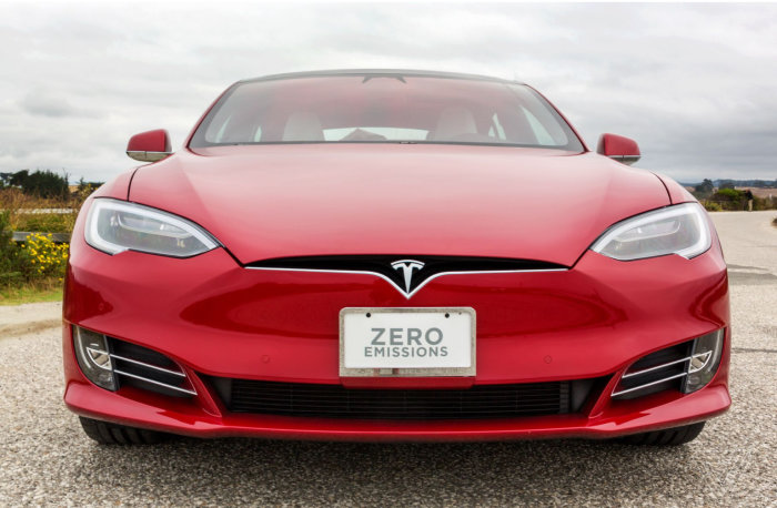 Röd Tesla-elbil framifrån med registreringsskylt som lyder "ZERO EMISSIONS".