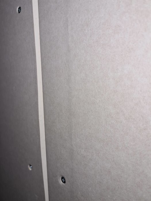 Två vertikala gipsskivor monterade på vägg, den vänstra med manuellt skuren fasning, den högra med fabriksfasning.