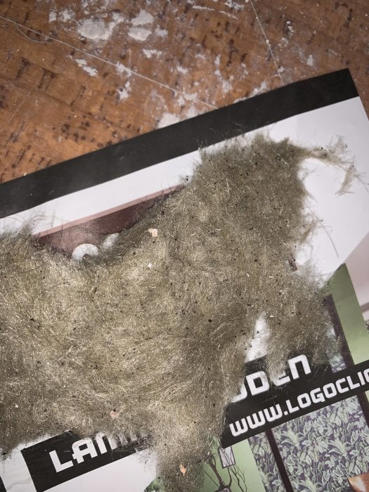 Gammal isoleringsmaterialbit på en tryckt broschyr, möjlig asbest eller sten/glasull från 60-talet.