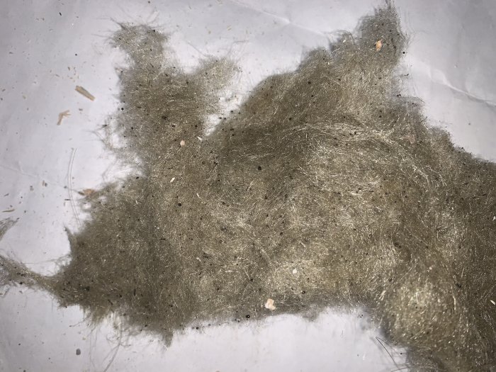 Gammal isolering från 60-talet på vit bakgrund, frågeställare undrar om det är asbest eller stenull/glasull.