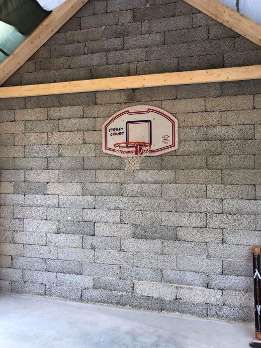 Basketkorg monterad på en grå betongmur i ett garage under konstruktion.