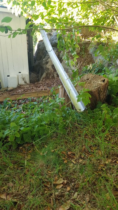 En lång hängränna dras från ett litet hus genom grönska fram till tomtgränsen.