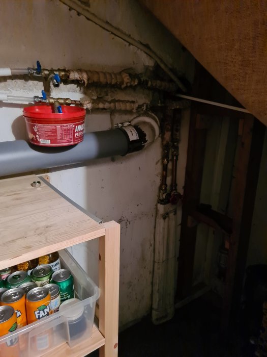 Radiatorrör anslutna i ett garage, inklusive fläktkonvektor och rörsystem, med synliga tecken på läckage och vattenskador.