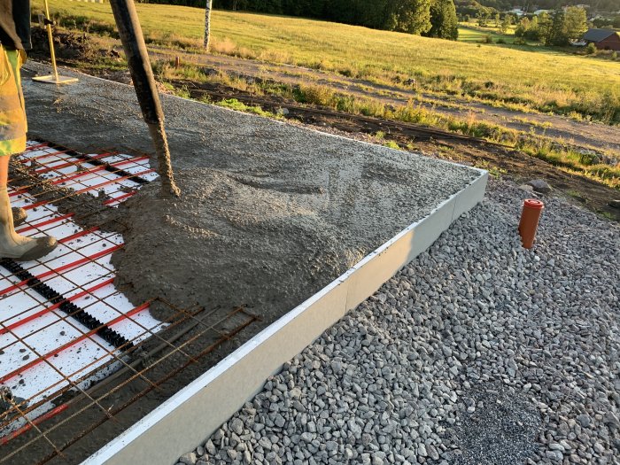 Gjutning av betong i kantbalkar på byggplats med armering synlig och vattenslang i förgrunden.