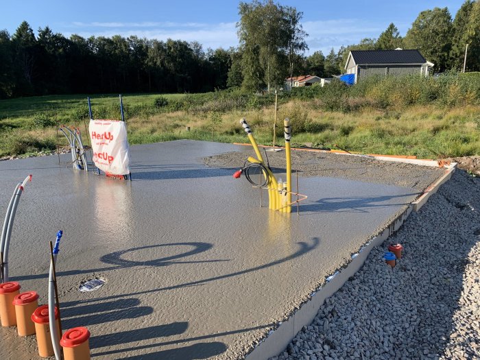 Nyutgjuten betong för grund med kantbalkar och installationer, solig byggarbetsplats.