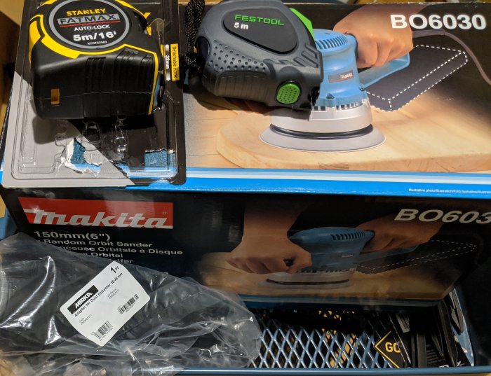 Makita excenterslip och Festool-slip med Stanley måttband och verktygslåda i bakgrunden.