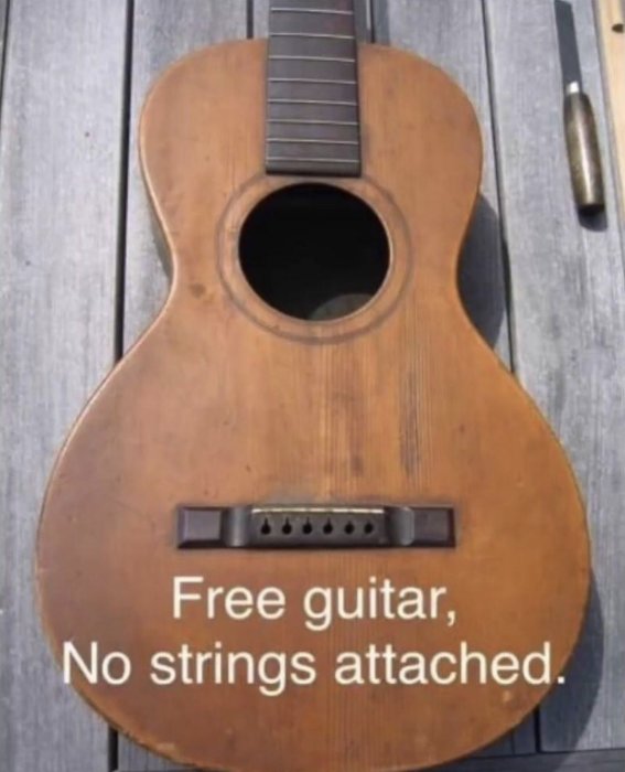 En gammal gitarr utan strängar med texten "Free guitar, No strings attached" på kroppen.