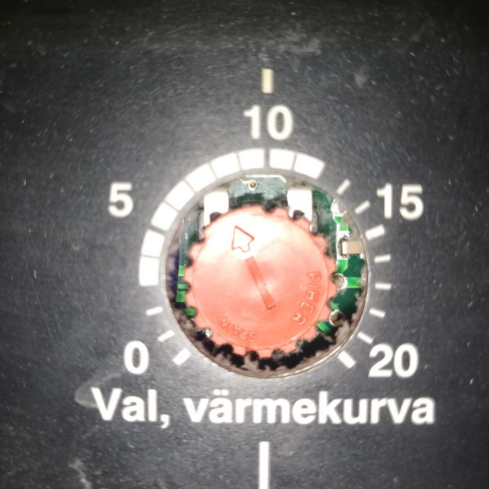 Reglage för värmekurva med pilen inställd på 5, utan synlig ratt för justering, mot bakgrund av termostatskalor.