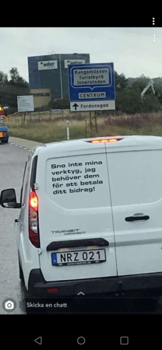 Vit skåpbil med texten "Snö inte mina verktyg, jag behöver dem för att betala ditt bidrag" och trafikskyltar i bakgrunden.
