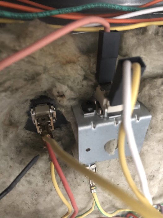 Två elektriska uttag i en vägg, den vänstra demonterad och den högra monterad med kablar anslutna.