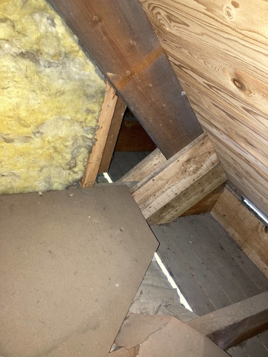 Öppen takfot med synlig isolering och takstolar innan installation av trygghetsvakt.
