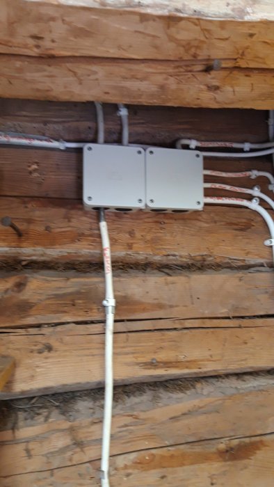 Elledningar och kopplingsdosa installerade på trävägg, ett renoveringsprojekt nära färdigställande.