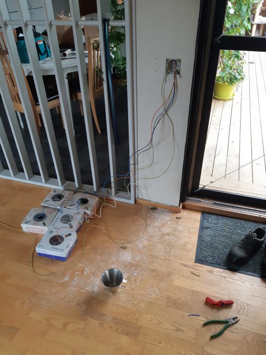 Elarbete på golv med urdragna sladdar, eluttag, verktyg och hål i golv och vägg.