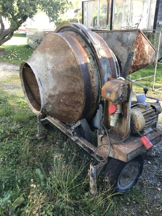 Gammal Torno K 150 betongblandare med rost och slitagetår på en grusig mark med gräs i bakgrunden.