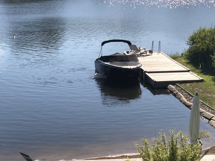 En motorbåt förtöjd vid en 3m bred träbrygga vid en sjö med planer på att förlänga och höja bryggan.