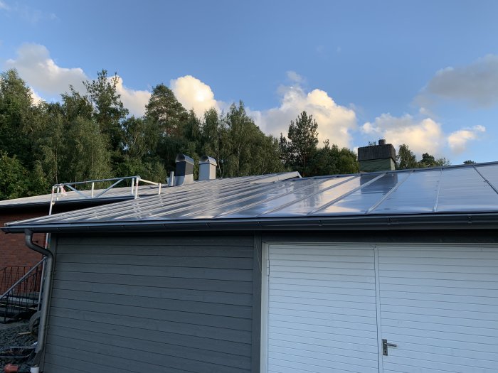 Antracitfärgat aluminiumtak från Lindab på hus med synliga monteringsdetaljer och ojämn yta mot himmel.