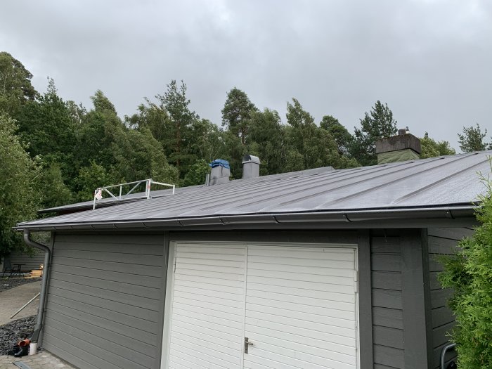 Plåttak i antracit metallic ovanpå en garagebyggnad, med synliga vågor och ojämnheter i materialet.