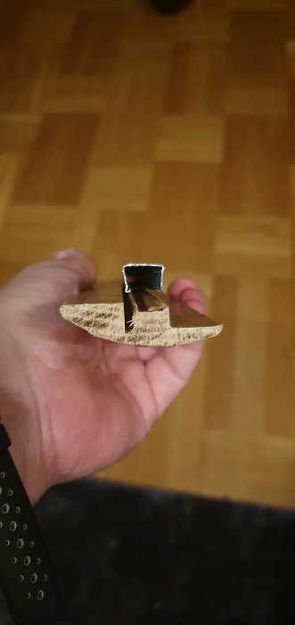 Hand håller en tröskellist avsedd för nivåskillnader mellan golv.