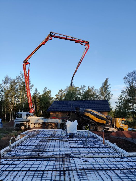 Betong hälls från cementbil genom betongpump till armeringsjärn på byggplats.