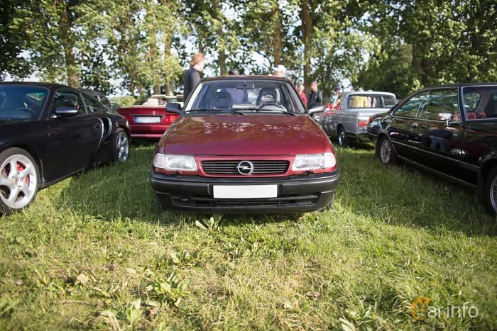 Röd Opel Astra GL från 1997 parkerad på gräs med andra bilar i bakgrunden på en bilträff.