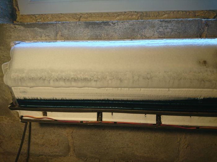 Avfuktare i källare täckt av ett tjockt lager is, visar konsekvens av saknad frostsensor.